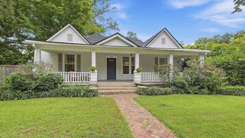A two-story house with a front porch, a brick pathway leading to the entrance, and a well-maintained lawn.