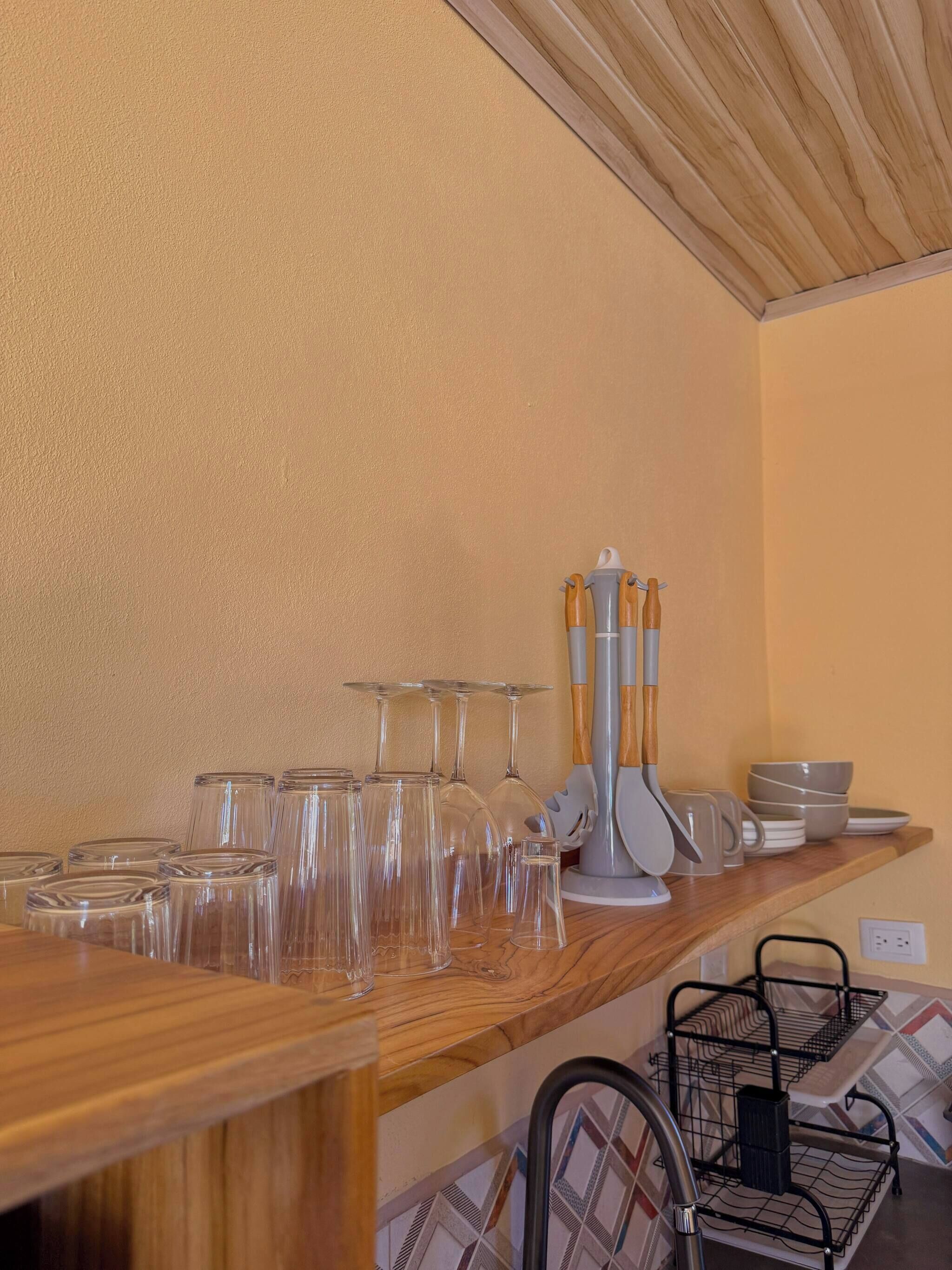 Un taulell de cuina amb diferents recipients de vidre, una cafetera i una prestatgeria metàl·lica.