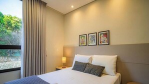 Een hotelkamer met een bed, een nachtkastje, een lamp en drie foto's in lijsten aan de muur.