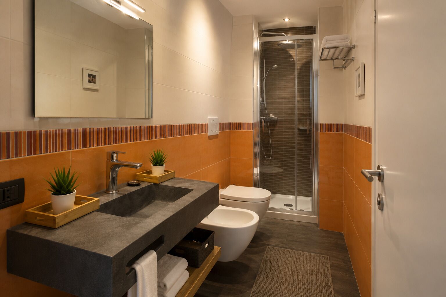 Een moderne badkamer met douche, toilet en wastafel.