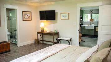 A bedroom with a bed, a bedside table with a lamp, a chair, and a television on the wall.