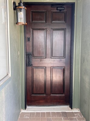 A dark wooden door with a metal handle and a keyhole, a small window above it, and a green-painted wall.