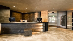A reception area with a counter, a computer, and a seating area. - Hotel Area One Ise Inter (Ise)