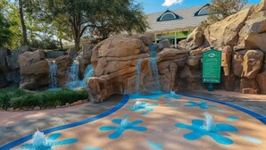 Una fuente rodeada de rocas grandes y un área pavimentada con diseños azules.