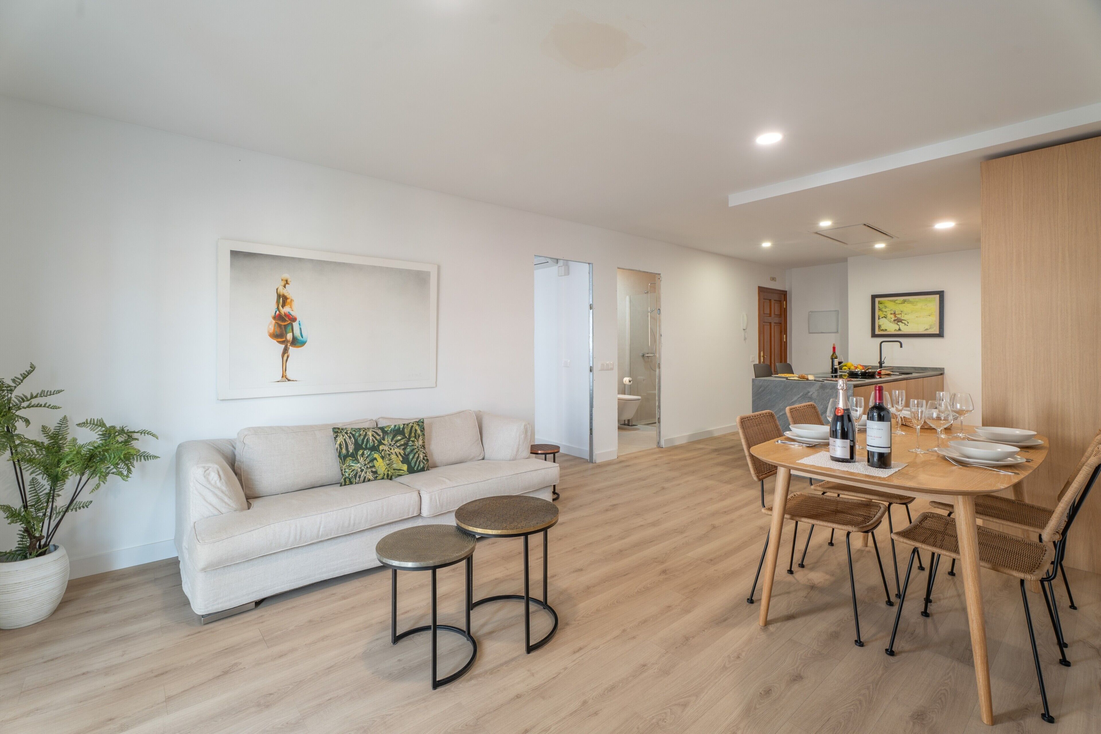 Een moderne woonkamer met een bank, salontafel en een eetgedeelte met stoelen en een tafel gedekt voor een maaltijd.