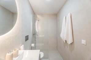 Een moderne badkamer met douche, toilet en wastafel.