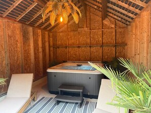 Une salle de spa en bois équipée d’un jacuzzi, de deux fauteuils et d’un banc.