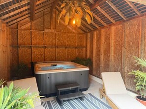 A hot tub in a wooden room with a bench and a chair.