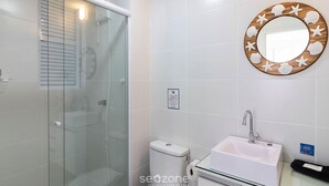 A bathroom with a glass shower enclosure, a toilet, a sink with a mirror, and a wall-mounted toilet paper holder. - Apt. in Cond. w/ Pool & sea View Cib21204 (Barra Velha)