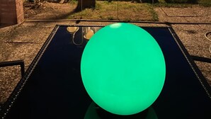 A backyard with a trampoline, outdoor furniture, and a large illuminated globe.