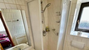 A bathroom with a shower, two sinks, a toilet, and a mirror.