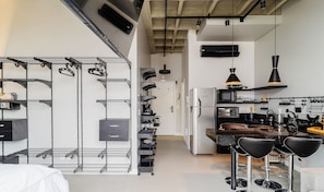 Uma cozinha moderna com eletrodomésticos de aço inoxidável, banquetas pretas e um mezanino com prateleiras de metal.