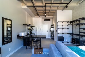 Una cocina moderna con una isla central, taburetes de bar y una zona de estar con sofá y una mesita.