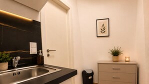 Uma cozinha moderna com bancada preta, pia de aço inoxidável e armário com gavetas.