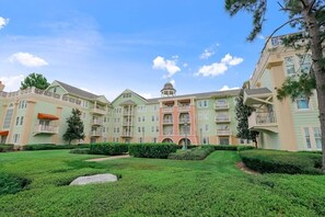 A multi-story hotel with a central courtyard, balconies, and a dome structure. - Orlando | Family Theme Park Stay | Pool + Spa | 2BR (Lake Buena Vista)