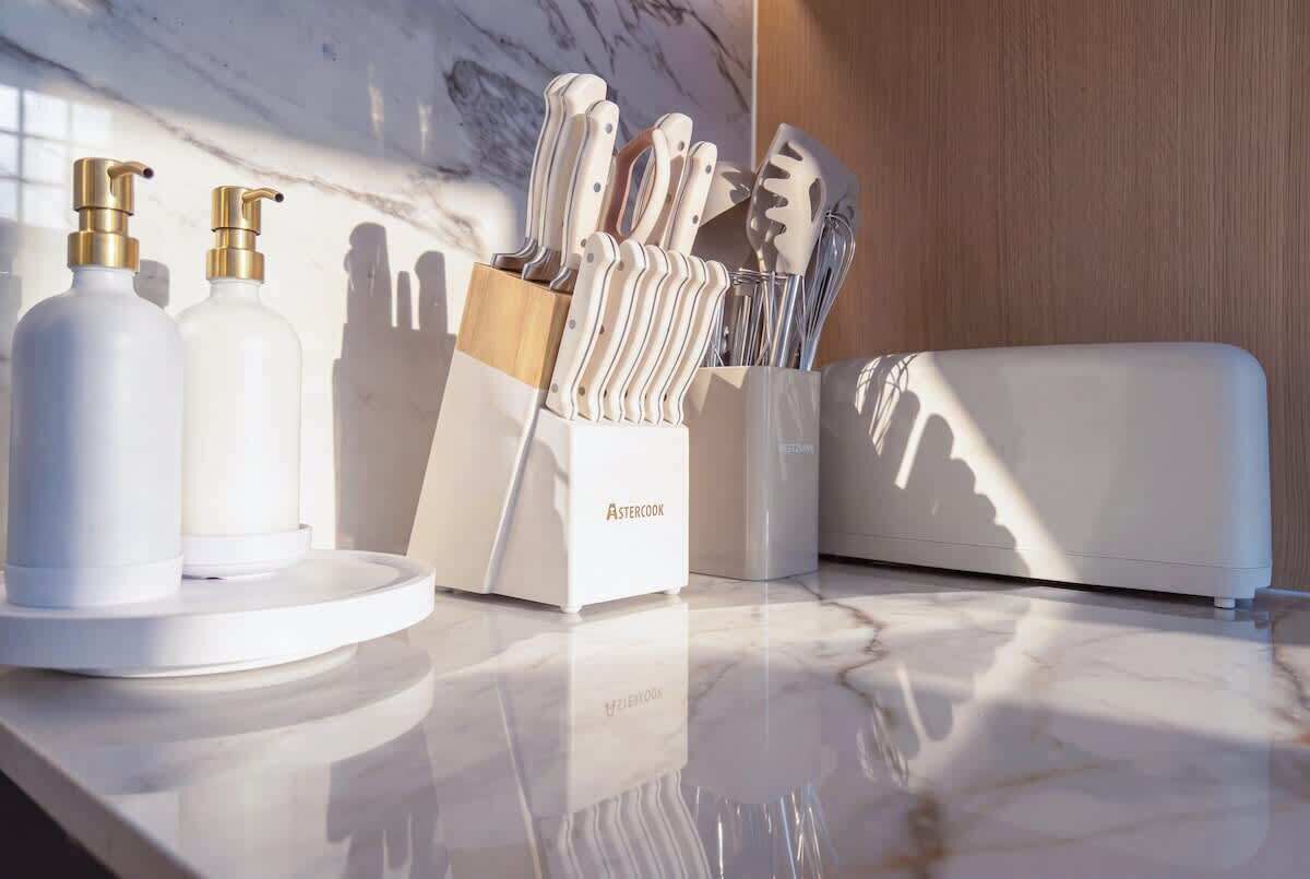 Un plan de travail de cuisine avec un range-couteaux, deux distributeurs de savon et un appareil électroménager blanc.