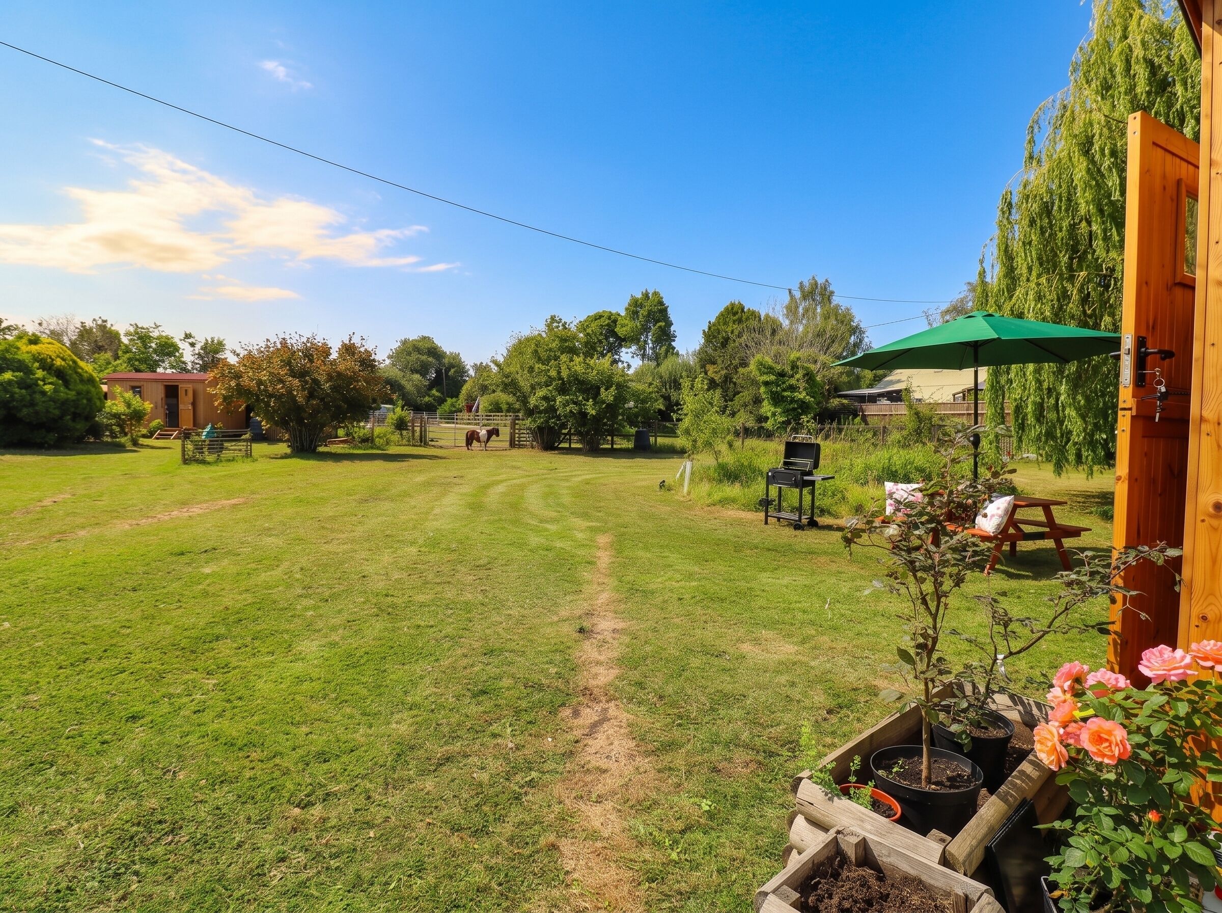 A well-maintained grassy yard with a wooden fence, a picnic table, and a barbecue grill.