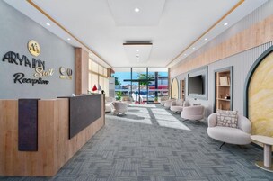 Ein moderner Empfangsbereich mit Rezeptionstresen, einer Sitzecke und großen Fenstern mit Blick ins Freie.