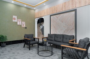 Un área de recepción con un conjunto de sofás, sillas, una mesita y una escalera.