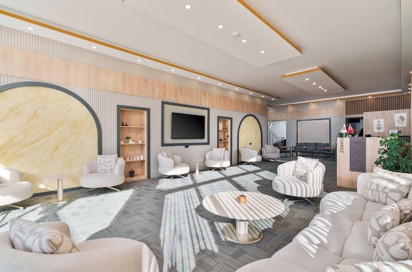 A modern living room with sofas, armchairs, a flat-screen TV, and a fireplace.