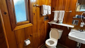 A wooden-paneled bathroom with a toilet, sink, and window. - Cozy 1BR hotel room, Hamilton - #348 Iroquois (Hamilton)