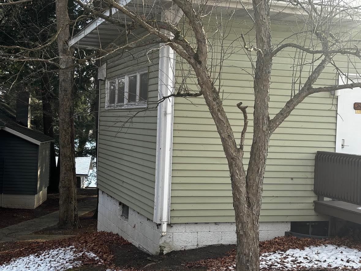 Una casa con un porche pequeño y un árbol en frente.