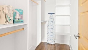 Passadís estret amb terra de fusta, parets blanques i una porta amb interruptor.