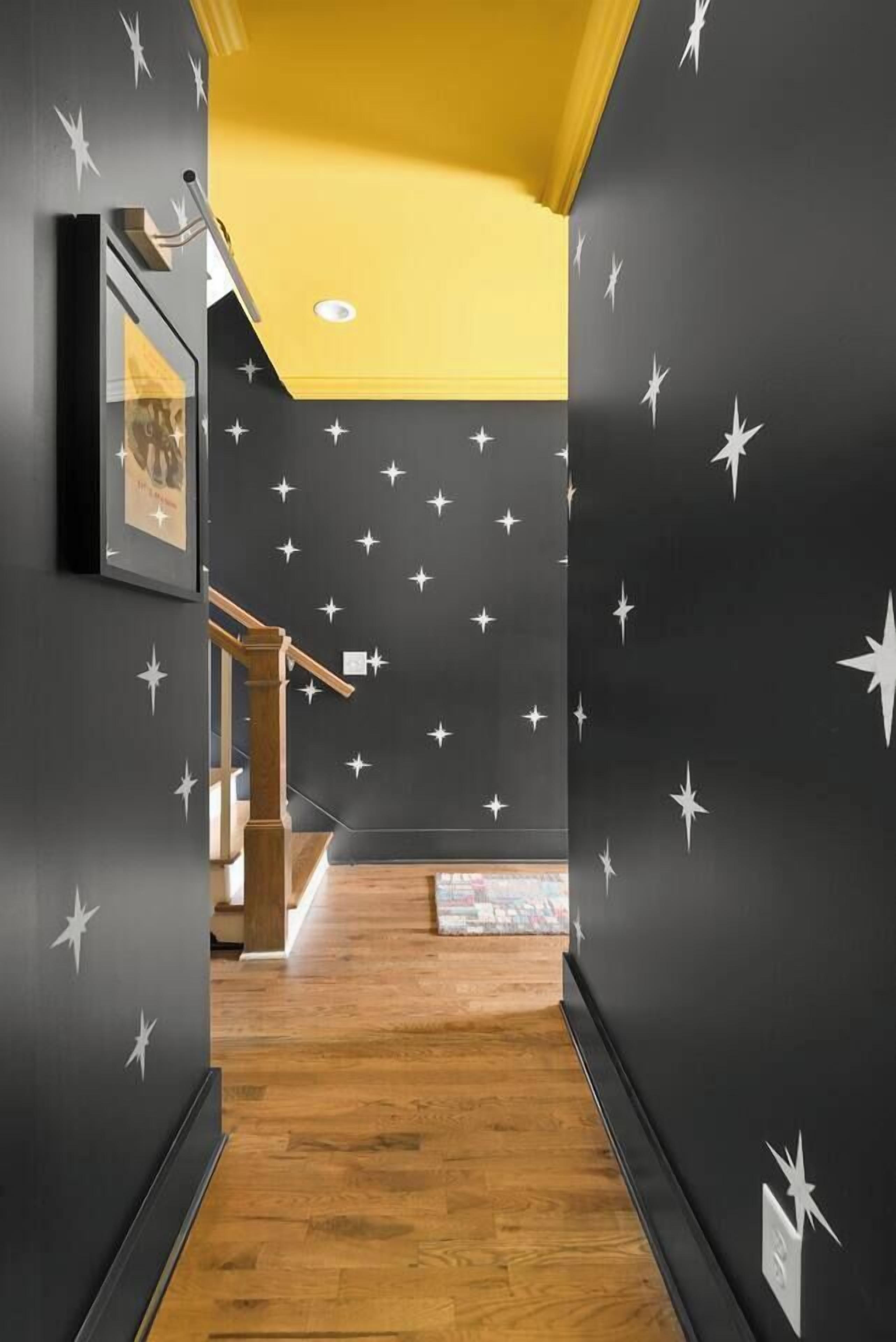 Un pasillo con estrellas decorativas en las paredes, piso de madera y una escalera con barandillas de madera.