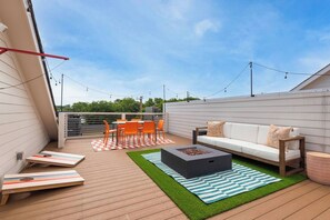 Eine Dachterrasse mit Feuerstelle, Sitzgelegenheiten im Freien und Blick auf den Himmel.