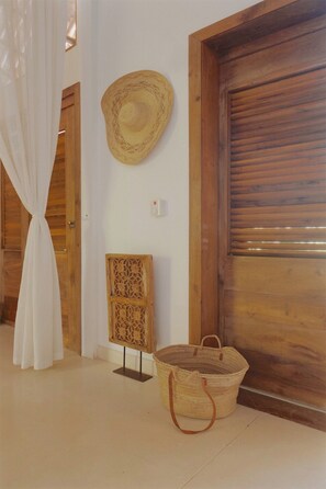 A room with a wooden door, a woven basket, a decorative panel, and a curtain. - 2-bedroom apartment in soothing Punta Cana with AC and gym access (Punta Cana)