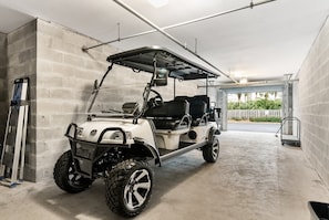 Ein Golfmobil steht in einer Garage mit Betonwänden und einem Metalldach.