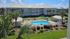A hotel with a swimming pool, multiple balconies, and palm trees. - 202C - Drift Aweigh *Golf Cart Included* (Miramar Beach)