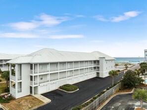 A multi-story hotel with balconies, a parking lot, and a view of the ocean. - 202C - Drift Aweigh *Golf Cart Included* (Miramar Beach)