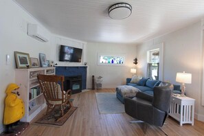 Ein Wohnzimmer mit Kamin, Fernseher, Sofa und Sessel.