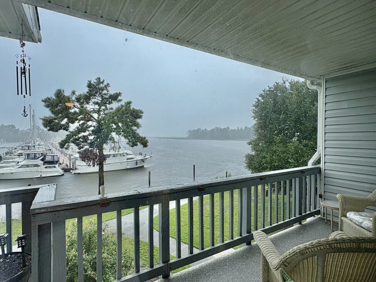 A covered porch with a view of a marina and a boat.