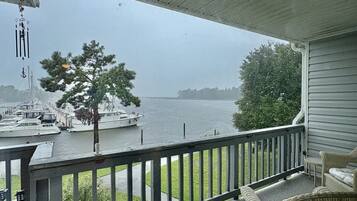 A covered porch with a view of a marina and a boat.