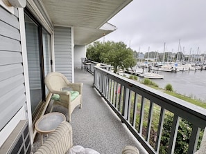 A balcony with wicker furniture, a view of a marina with boats, and a cloudy sky. - Marina-view condo in Fairfield Harbour (New Bern)