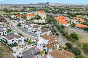 Ein Wohngebiet mit modernen Häusern, einer Hauptstraße und einem Golfplatz im Hintergrund.