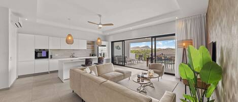 A modern living room with a sofa, a dining table, and a kitchen in the background.