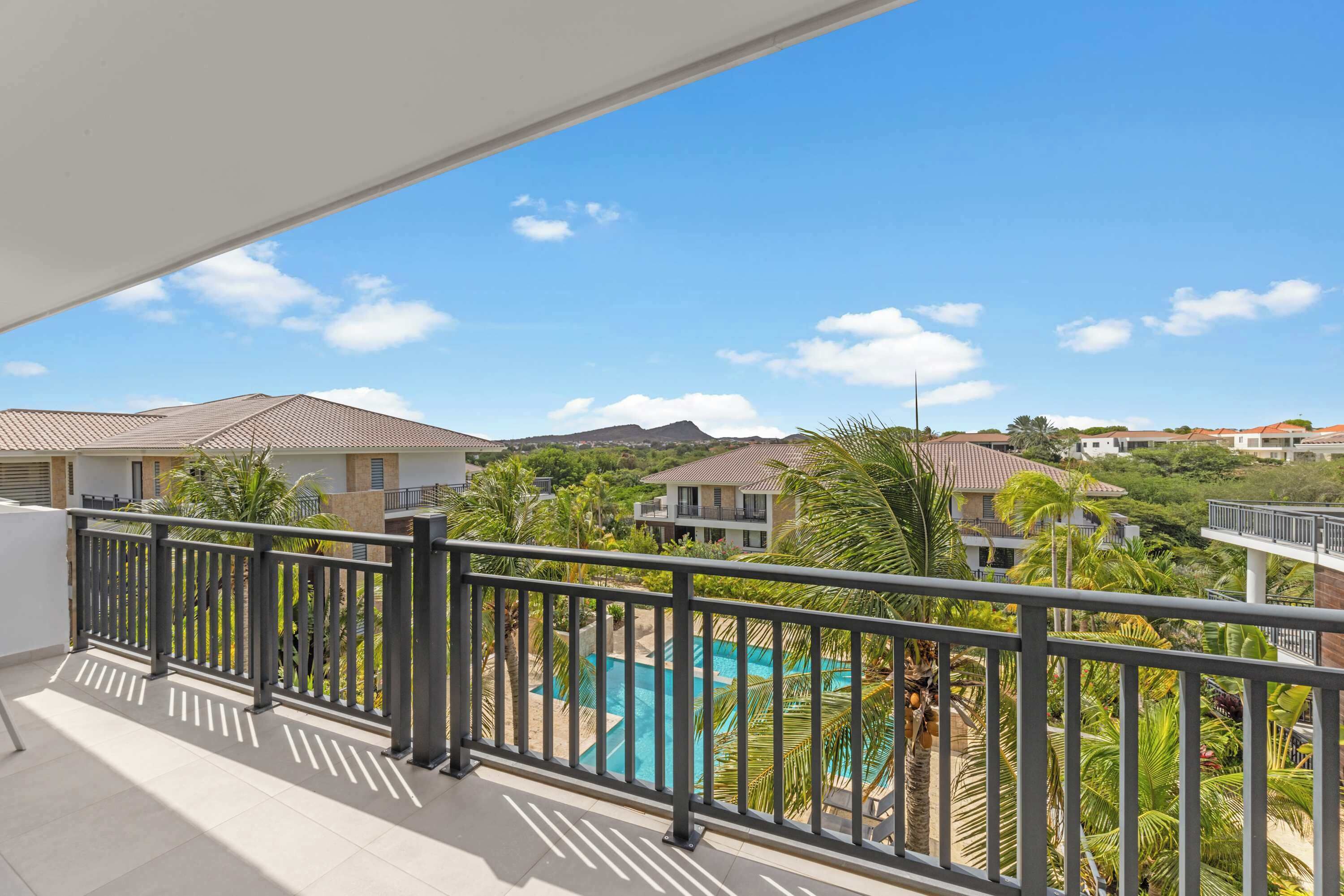 Ein Balkon mit Blick auf einen Swimmingpool und umliegende Gebäude.