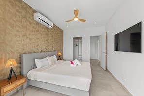 Ein modernes Schlafzimmer mit einem Bett, Nachttischlampen, einem Deckenventilator und einem an der Wand montierten Fernseher.
