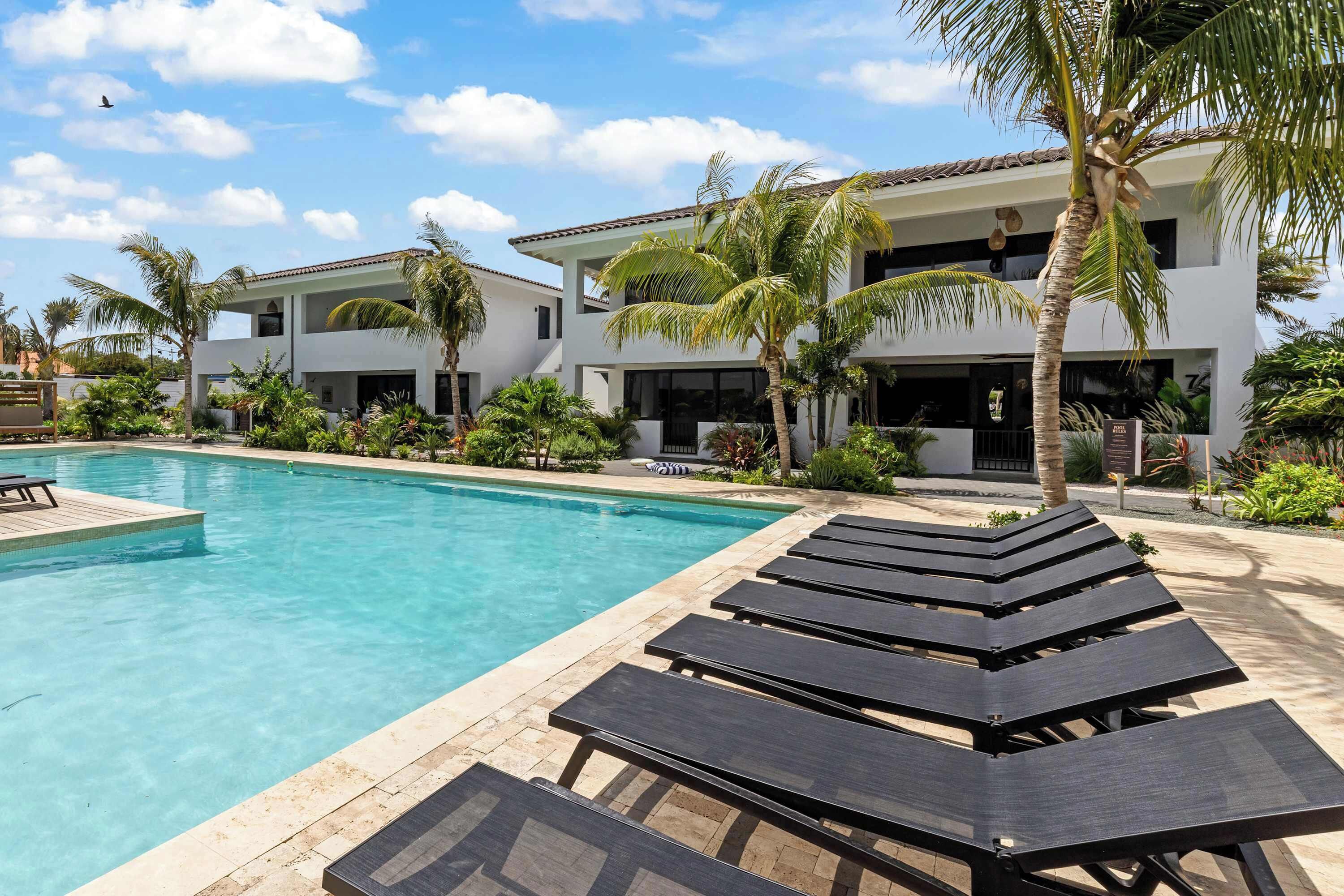 A swimming pool with lounge chairs and palm trees.