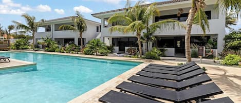 A swimming pool with lounge chairs and palm trees.