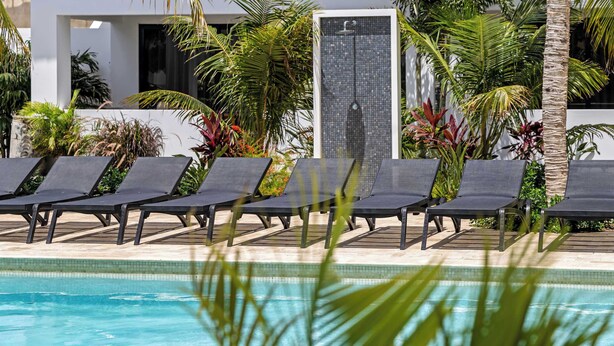 Un área de piscina con sillones de descanso y una pared de azulejos.