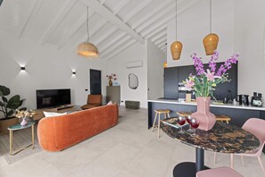 Ein moderner Wohnraum mit Sofa, Fernseher, Essbereich und Küche.