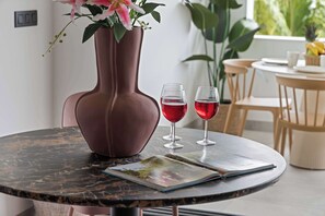 Ein runder Tisch mit einer Vase, zwei Weingläsern und einer Zeitschrift.