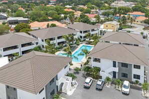 A residential area with multiple two-story buildings, a swimming pool, and parked cars. - Sunset Pearl Curaçao | Pool & Free Parking (Mahaai)