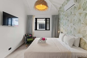Ein modernes Schlafzimmer mit einem Bett, einem an der Wand montierten Fernseher, einem Fenster mit Vorhängen und einer Wandklimaanlage.