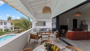 Un espacio exterior moderno con piscina, una mesa de comedor con fruta y vistas a un edificio residencial.