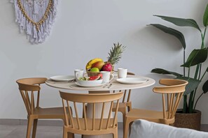 Ein runder Esstisch mit vier Stühlen, einer Obstschale und zwei weißen Tassen darauf.